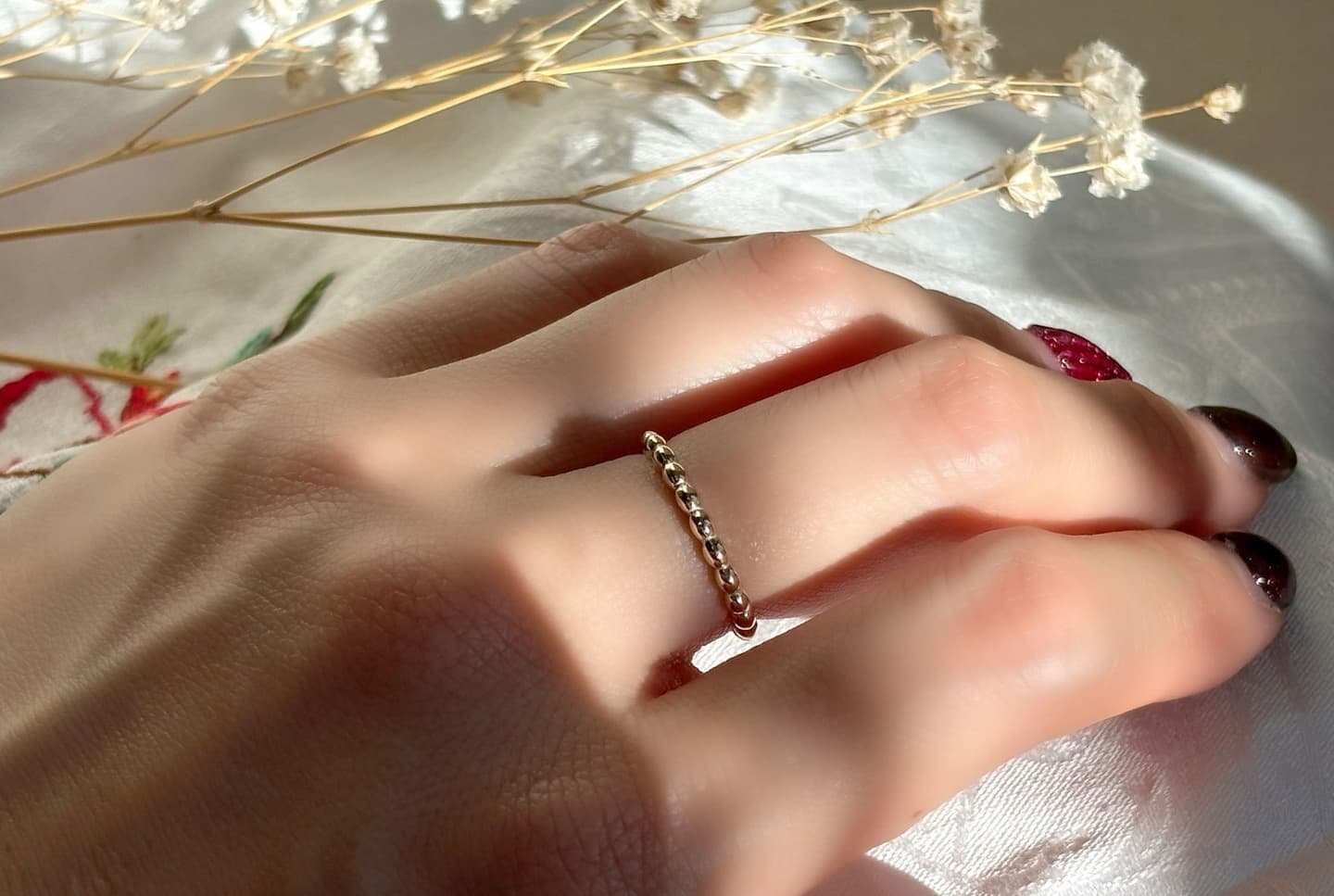 楕円を連ねたデザインのK10で作られた指輪、Ellipse Harmonyを中指に着用している写真